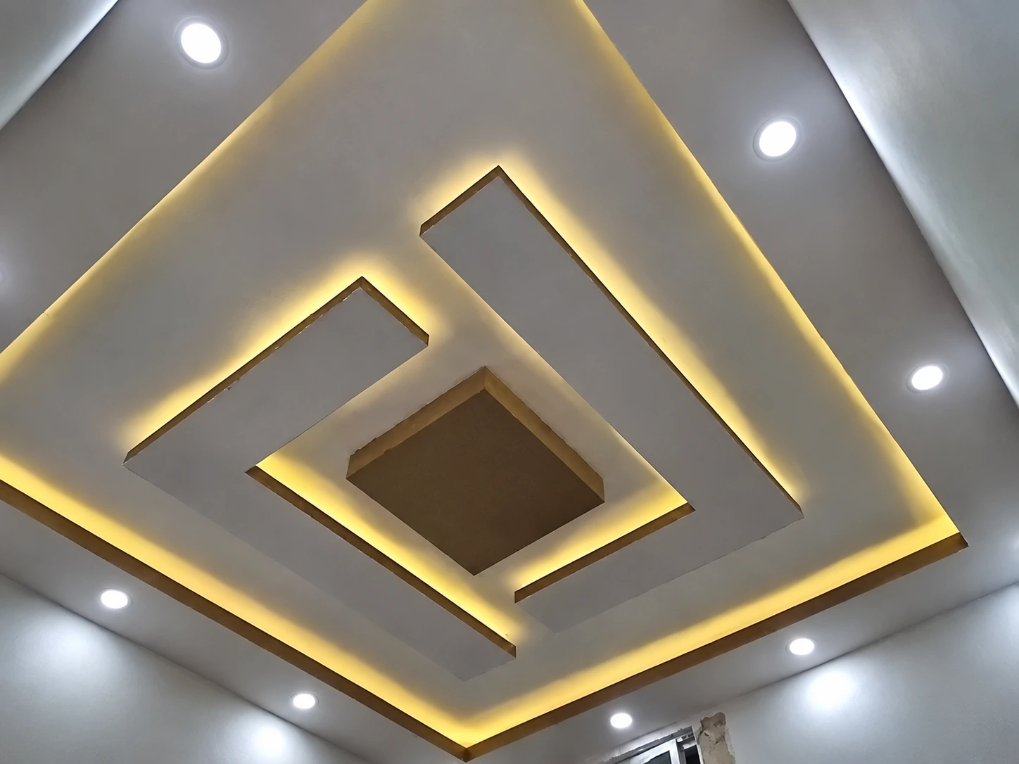 Geometric ceiling with warm concealed lighting and downlights